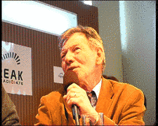 Hubert Wallner, ein älterer Redakteur mit Sakko und akkuratem Haar, spricht ins Mikrophon