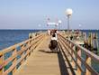 Frau im Rollstuhl steht am Pier und schaut auf das Meer hinaus