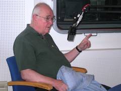 ein älterer Herr mit grünem Poloshirt und Brille diskutiert vor einem Mikrophon und gestikuliert mit dem Zeigefinger