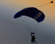 Ein Fallschirm mit zwei Menschen vor einer finsteren Wolke