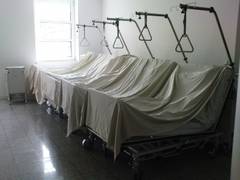 Mit weißen Leintüchern bedeckte Krankenbetten stehen in einer Reihe