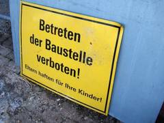 gelbes Schild mit der Aufschrift: Betreten der Baustelle verboten