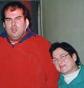 ein großer relativ beleibter junger Mann im roten Pullover und eine viel kleinere Frau im blauen Pullover