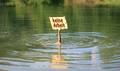 Hand mit beschriftetem Schild ragt aus Wasser