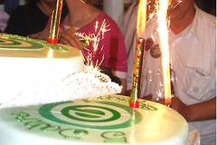 Mit Zuckerguss überzogene Torte, die das Logo von equalizent trägt; darauf Sprühkerzen