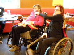 Zwei Rollstuhlfahrerinnen sprechen, eine hält ein Mikrophon
