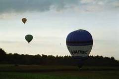 Heißluftballon hebt gerade ab, im Hintergrund 2 Ballons in der Luft