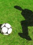 Fußball auf Rasen mit Schatten eines Spielers